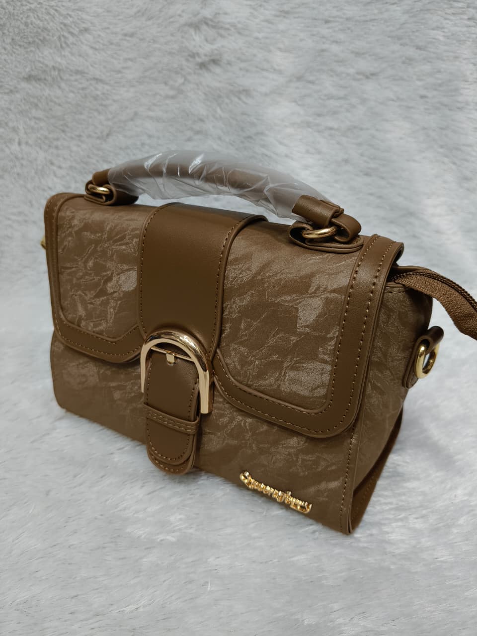 Brown handbag with gold accents on a gray background