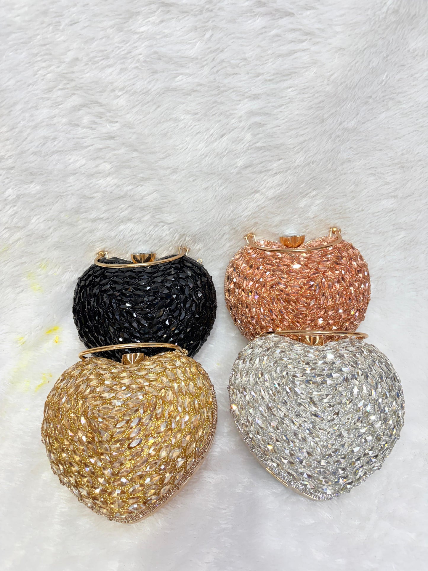 Four glittery handbags in black, gold, rose gold, and silver on a textured white background.