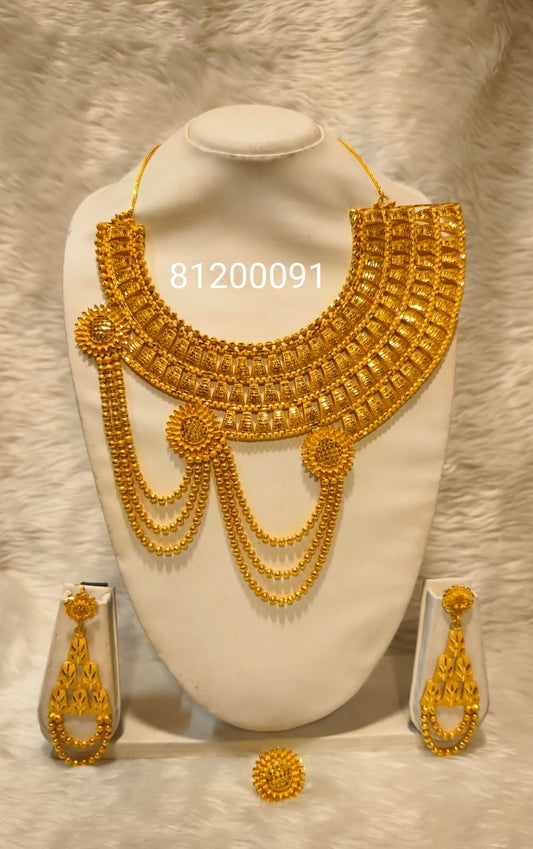 Gold necklace and earrings set on a white stand with a blurred background
