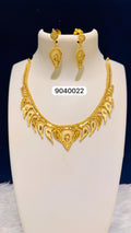 Gold necklace and earrings set on a white stand with a dark blue background