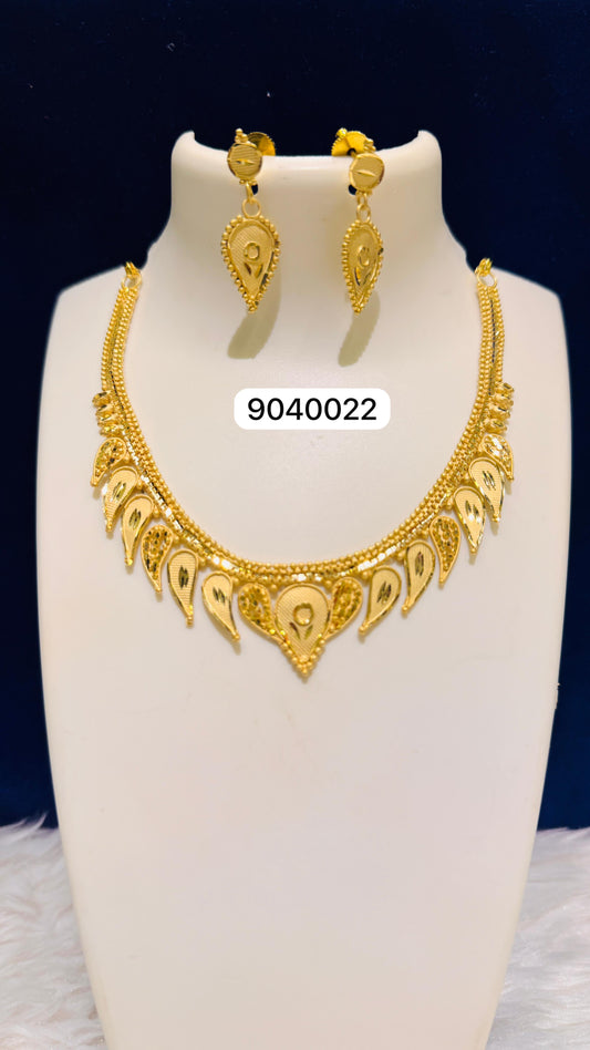 Gold necklace and earrings set on a white stand with a dark blue background